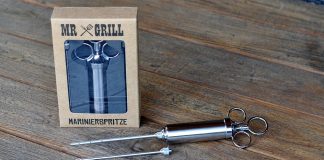 Mr Grill Marinierspritze aus Edelstahl mit Verpackung und zwei Injektionsnadeln auf Holzuntergrund
