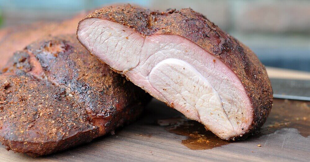 Aufgeschnittenes Puten-Pastrami mit dunkler Gewürzkruste und zartem, rosa Fleisch auf Schneidbrett