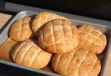 Lepinje-Fladenbrot aus dem Ofen mit goldbrauner Kruste und Schnittmuster, auf Tablett angerichtet