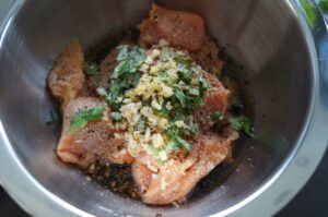 Hähnchenbrust mit Rub aus Paprika und Gewürzen, garniert mit frischen Kräutern und Knoblauch in einer Metallschüssel vor dem Grillen