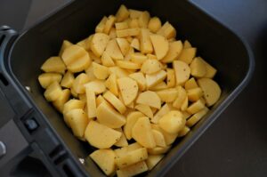 Gewürfelte Kartoffeln mit Pfeffer in schwarzem Heißluftfritteusen-Korb