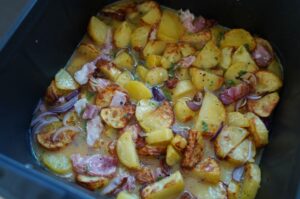 Bauernfrühstück in der Heißluftfritteuse: Erdäpfel mit Speck, Zwiebeln und Kräutern gebräunt, in schwarzer Pfanne