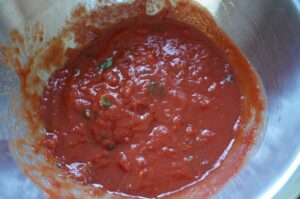 Selbstgemachte Pizzasauce in Edelstahltopf mit Tomaten, Kräutern und Gewürzen