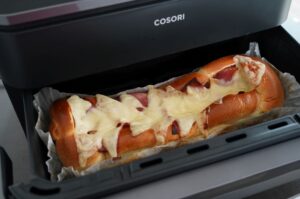Gefüllter Brioche-Hefezopf mit Ei und Käse im geöffneten COSORI-Toaster, geschmolzener Käse und Eigelb sichtbar