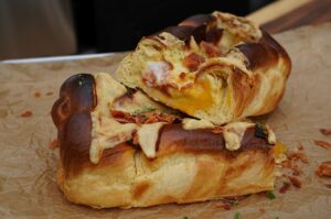 Gefüllter Brioche-Hefezopf mit Spiegelei, Käse und Speck auf Schneidebrett