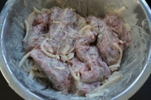 Rohe Spider-Steak-Spieße mit Zwiebeln in cremiger Mayonnaise-Marinade in einer Schüssel