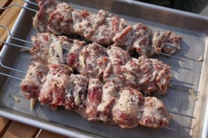 Spider-Steak-Spieße auf Grillspießen in Mayonnaise-Marinade, rohes Fleisch mit Gewürzen und Zwiebeln, bereit zum Grillen