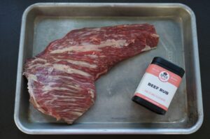 Rohes Tri-Tip-Steak mit Marmorierung auf Backblech neben Beef-Rub-Gewürzmischung