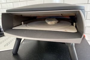 Panuozzo in einem geöffneten Pizzaofen auf der unteren Kochfläche mit aufgelegtem Stein zum Backen des neapolitanischen Pizza-Sandwichs