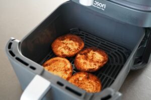Vier goldbraun frittierte Burger-Patties in der Heißluftfritteuse auf dem Gitterblech