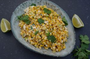 Esquites in grauem Teller: gegrillter Mais mit Feta, Koriander und Limette