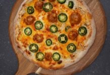 Jalapeno-Popper-Pizza mit geschmolzenem Käse, Pepperoni und frischen Jalapeno-Scheiben auf Holzbrett