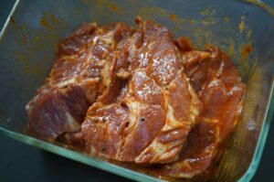 Nackensteaks in Glasschüssel mariniert mit Miso-Zwiebel-Marinade, glänzend und dunkelbraun gefärbt