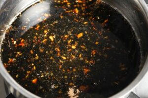Glasierte Yakitori-Sauce mit gehacktem Knoblauch und Chili in einem Topf