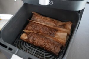 Drei Döner in Backpapier in der Heißluftfritteuse, goldbraun gebraten und fertig zum Servieren