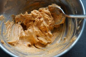 Cajun-Butter mit Würzspuren in Metallschüssel, cremige Konsistenz mit Rührschaufel