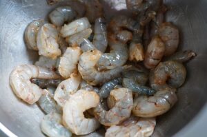 Angebratene Garnelen mit Cajun-Gewürzen und Butter in einer Metallschüssel