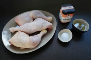 Rohe Hähnchenschenkel auf Teller mit Mayonnaise, Salz und Öl als Zutaten für die Heißluftfritteuse