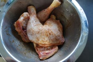 Gebratene Hähnchenschenkel mit Gewürzen in metallischer Schüssel, Haut knusprig braun und aromatisch würzig
