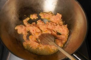 Gemahlenes Schweinefleisch wird in einem Wok mit Gewürzen und Chili angebraten, Zutat für Pad Kra Pao