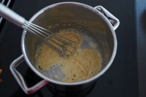 Béchamelsauce wird in Topf mit Schneebesen gerührt, cremige Konsistenz mit Butterflöckchen