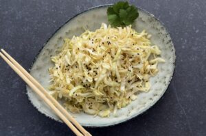 Japanischer Krautsalat in einer Schale, gewürzt mit schwarzem Sesam und Koriander, mit Essstäbchen