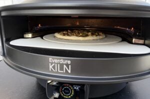 Smashburger-Pizza im Everdure KILN Pizzaofen mit Flammkuchen-Teig, Hackfleisch, Zwiebeln und Käse auf Pizzastein