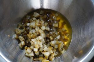 Gewürfelte eingelegte Gurken mit Öl in einer Metallschüssel für die Zubereitung von Pickle-Dip