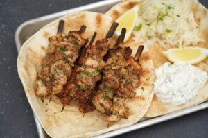 Gegrillte Gyros-Hähnchen-Spieße auf Fladen mit Tzatziki-Sauce und Zitronenscheiben