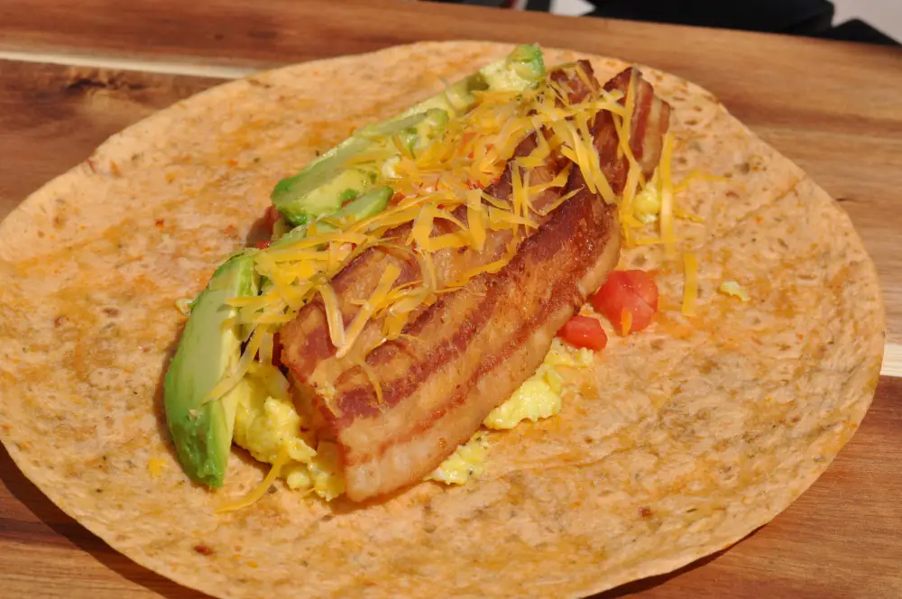 Frühstücks-Wrap mit Rührei, Bacon, Käse, Avocado & Tomate 3 Der Frühstücks-Wrap wird belegt