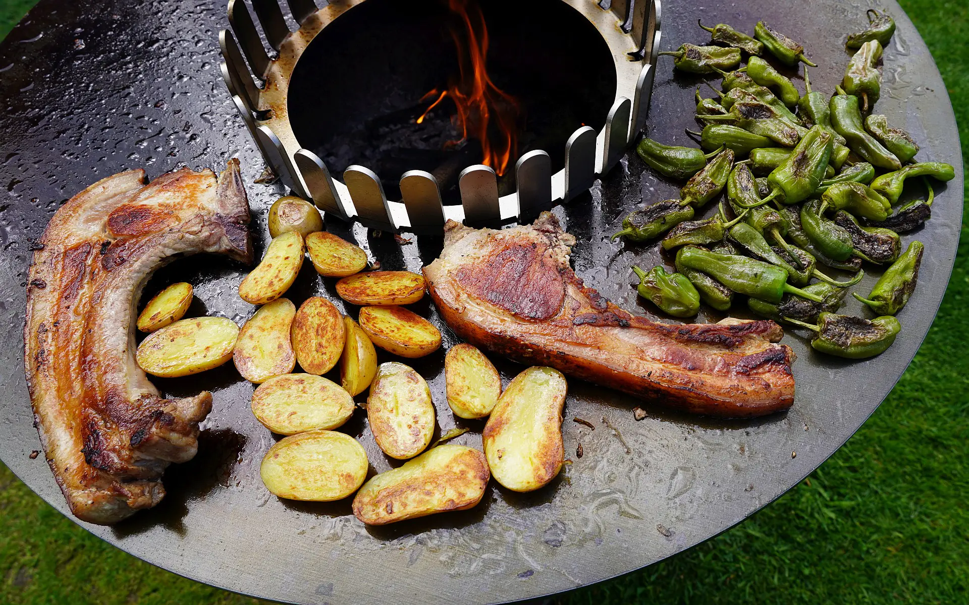 Tomahawk vom Schwein mit Bratpaprika und Grillkartoffeln | BBQPit.de feuerplatte-Tomahawk vom Schwein-Feuerplatte von Grillrost.com im BBQPit-Test