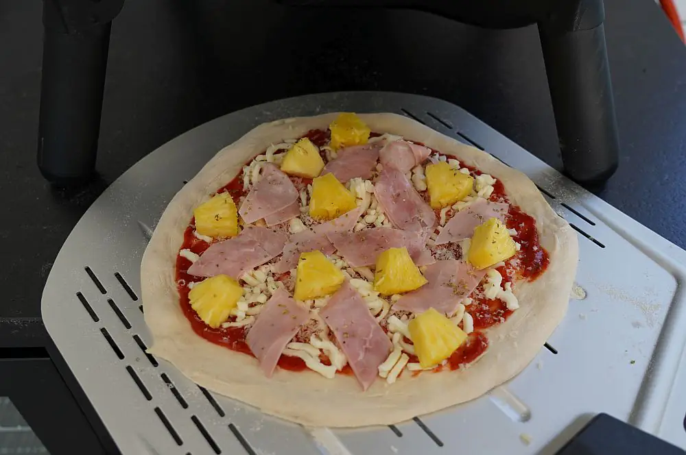 Pizza Hawaii mit Ananas und Schinken 3 Die Pizza Hawaii wird in den Pizzaofen geschoben
