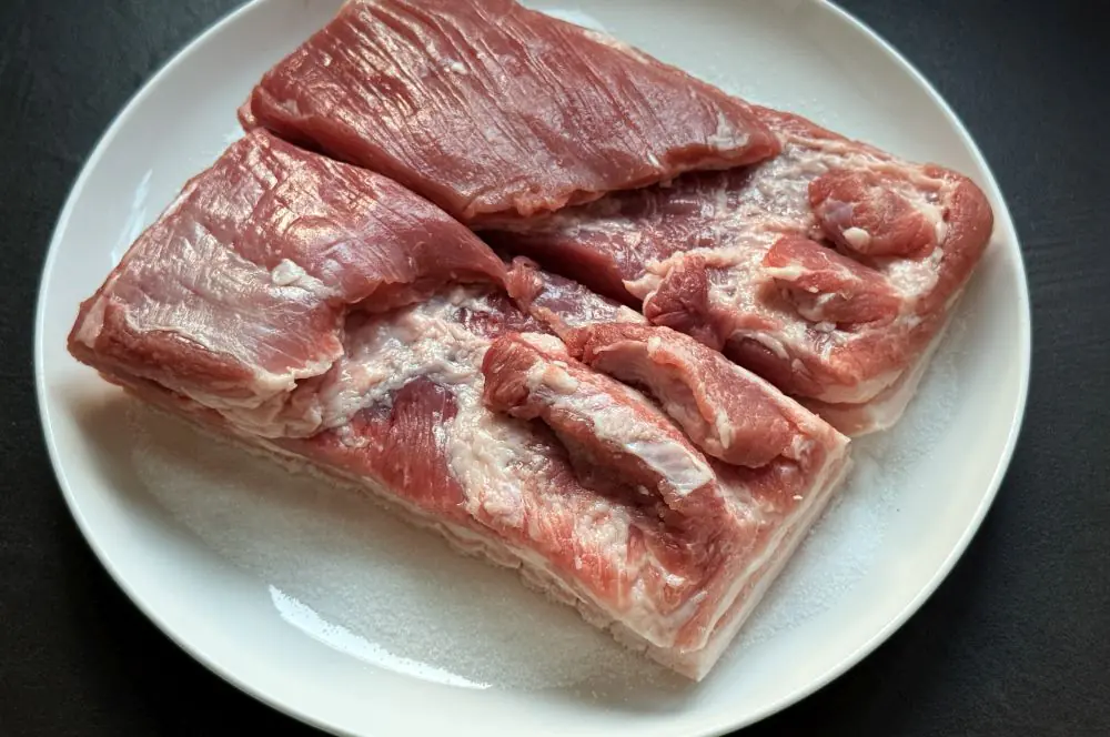 Knuspriger Schweinebauch aus der Heißluftfritteuse 3 Der Schweinebauch wird mit der Schwarte auf ein Salzbett gelegt