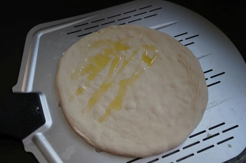 Die Hälfte des Pizzateiges wird mit Olivenöl benetzt