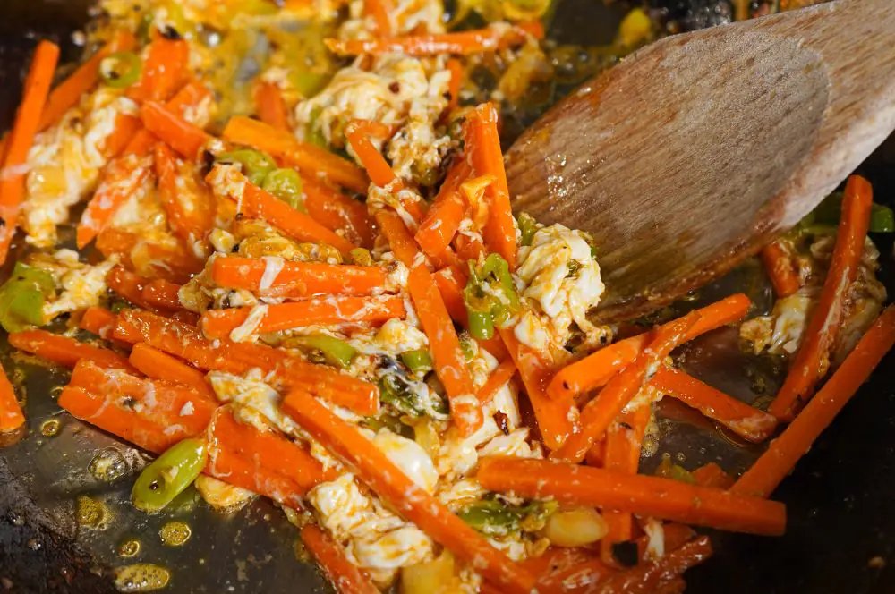 Ei und Gemüse kommen in den Wok