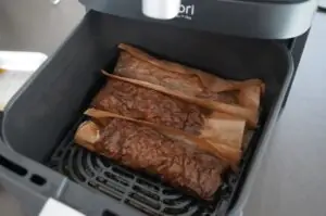 Drei Döner in Backpapier in der Heißluftfritteuse, goldbraun gebraten und fertig zum Servieren