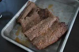 Gegrillte Döner-Fleischstücke auf Backpapier in Aluminiumbehälter, medium-rare Garstufe mit Grillmarks