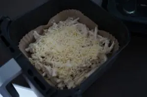 Überbackene Schupfnudeln mit geriebenem Käse auf Backpapier in Grillbehälter, Flammkuchen-Style zubereitet