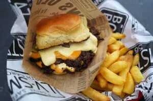 Gourmet-Smash-Burger mit geschmolzenem Käse, gegrilltem Patty und Bearnaise-Sauce auf Brioche-Bun, serviert mit knusprigen Pommes frites