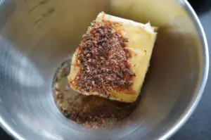 Butterblock mit Cajun-Würzmischung in Edelstahlschüssel, braunrote Gewürzpulver aufgestreut