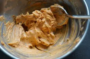 Cajun-Butter mit Würzspuren in Metallschüssel, cremige Konsistenz mit Rührschaufel