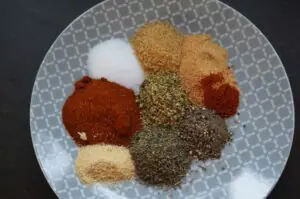 Cajun-Gewürzmischung auf grauem Teller: Paprika, Cayennepfeffer, brauner Zucker, Knoblauch- und Zwiebelpulver, getrocknete Kräuter, Salz und Gewürze