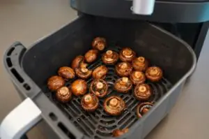 Ganze Champignons mit Knoblauch in der Air-Fryer-Schale, goldbraun gegrillt