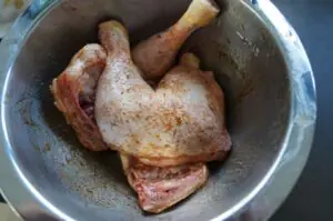 Gebratene Hähnchenschenkel mit Gewürzen in metallischer Schüssel, Haut knusprig braun und aromatisch würzig