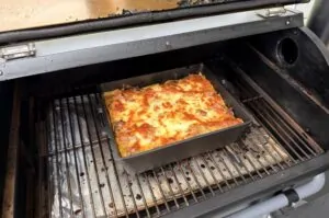 Gulasch-Lasagne - Das herzhaft überbackene Schmorgericht 15 Gulasch-Lasagne mit goldbrauner, überbackener Käsekruste in rechteckiger Form auf Grillrost im offenen Gasgrill