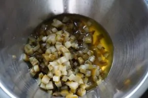 Gewürfelte eingelegte Gurken mit Öl in einer Metallschüssel für die Zubereitung von Pickle-Dip