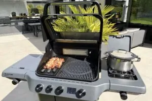 Rindfleischspieße mit Camembert und Bacon 11 Rindfleischspieße auf dem Grill eines Gasgrill-Systems mit Seitenbrenner und Topf auf der Terasse