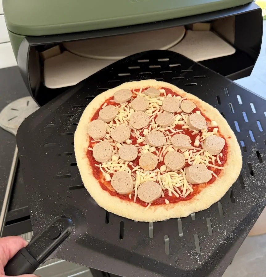 Die Currywurst-Pizza wird in den Pizzaofen geschoben