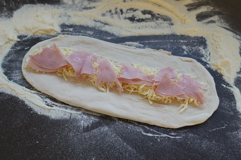 Der Pizzateig wird ausgeformt und belegt