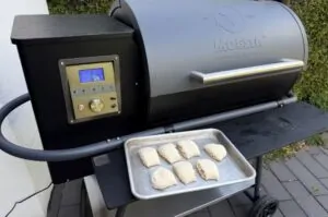 Pellet-Grill Moesta mit digitaler Kontrollanzeige und sechs Pizzabrötchen mit Schinken und Käse auf Backblech in der Einsatzmulde